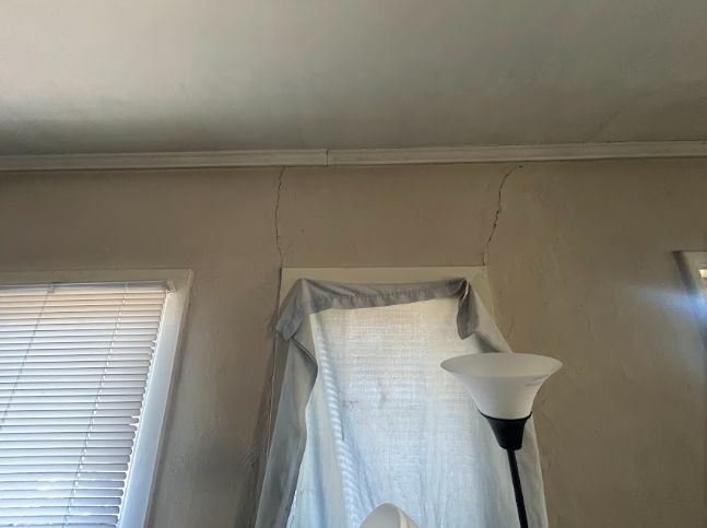 Diagonal cracking at the ceiling line near a window